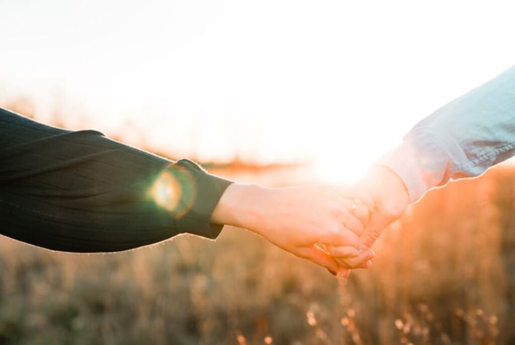 A man and a women with their arms reaching out holding hands