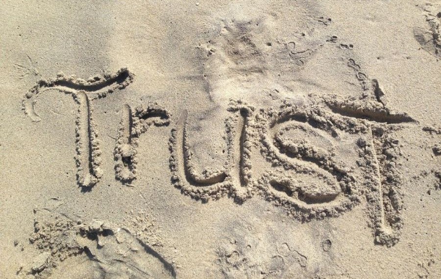 the word trust written in sand which represents an important step on how  to let go to manifest